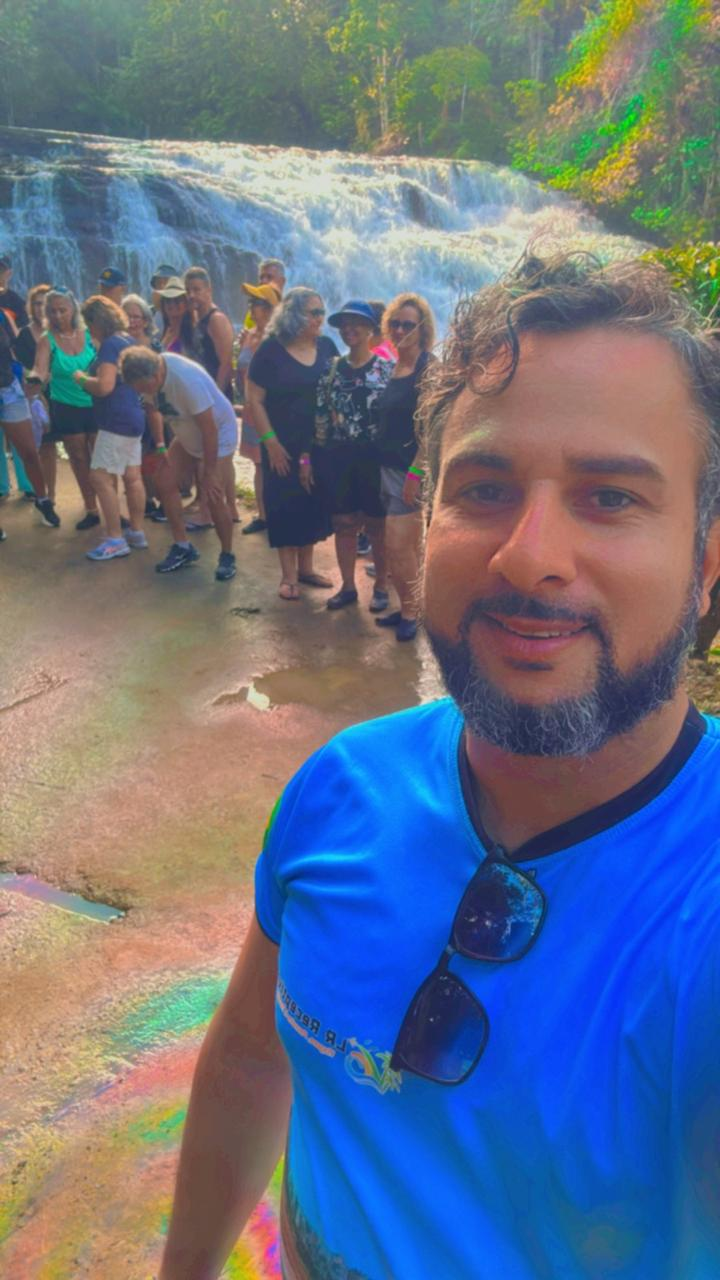 Guia da LR Transfer Ilhéus com um grupo de turistas em frente a uma cachoeira no sul da Bahia